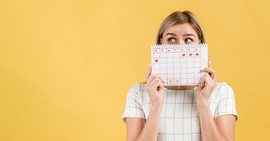 period-calendar-with-drawn-heart-shapes-woman-covering-her-face