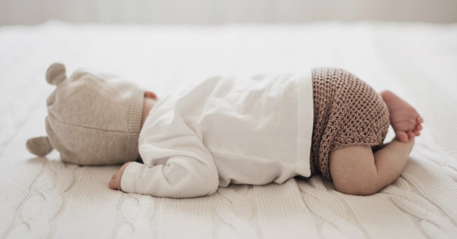 lovely baby in the hat sleeping on the bed