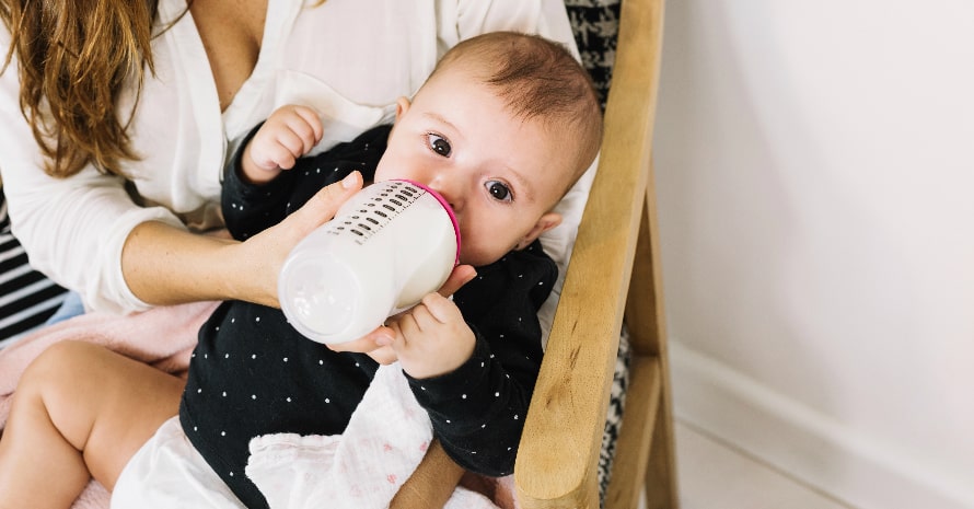 mom feeding her baby through the bottle of milk