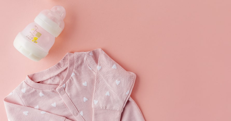 baby sweater and bottle on the pink background