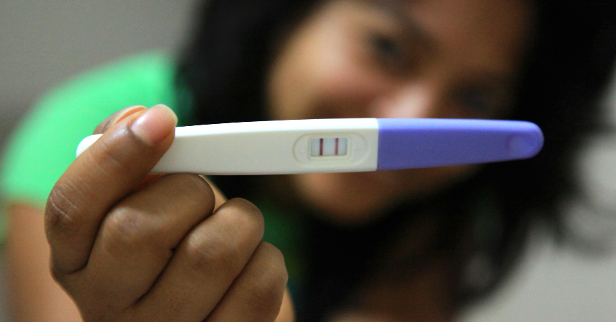 woman holding positive line pregnancy test