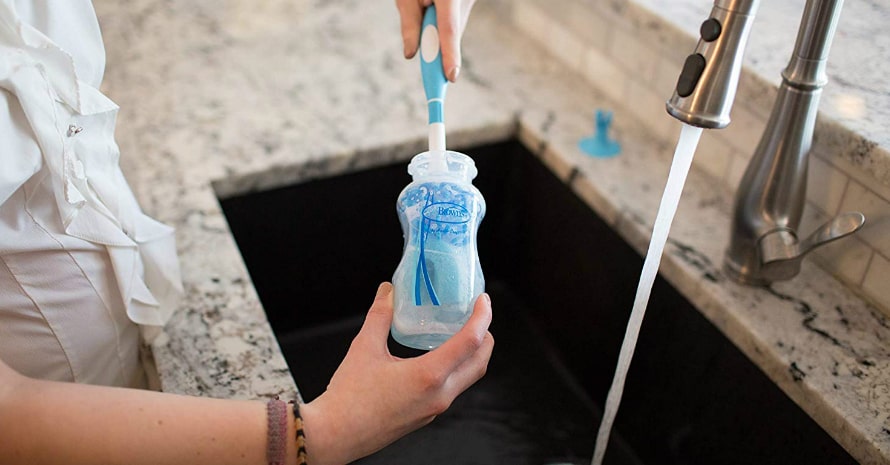 woman washing the baby bottle with blue bottle brush