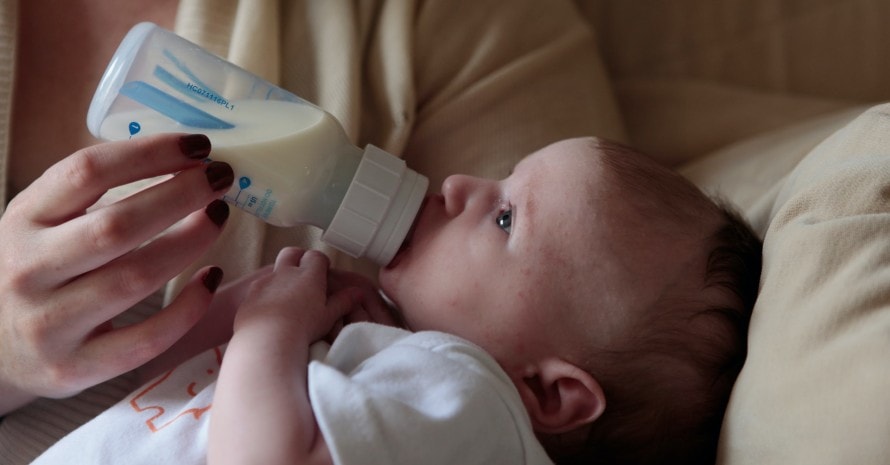 baby is being fed with the help of a baby bottle