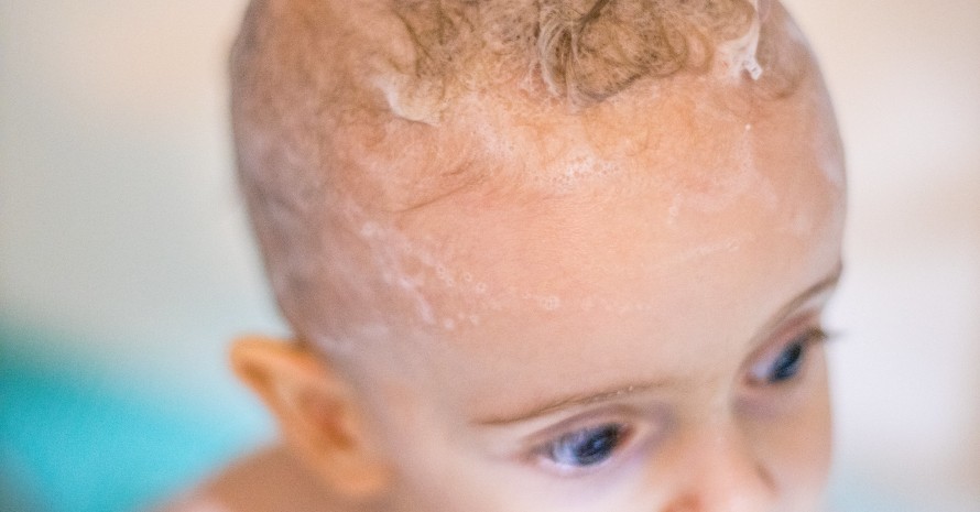 close-up photo of a little baby with shampoo foam in hair